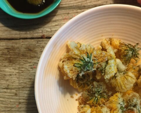 Dandelion tempura in a blush pink bowl with a dipping sauce