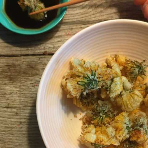 Dandelion tempura in a blush pink bowl with a dipping sauce