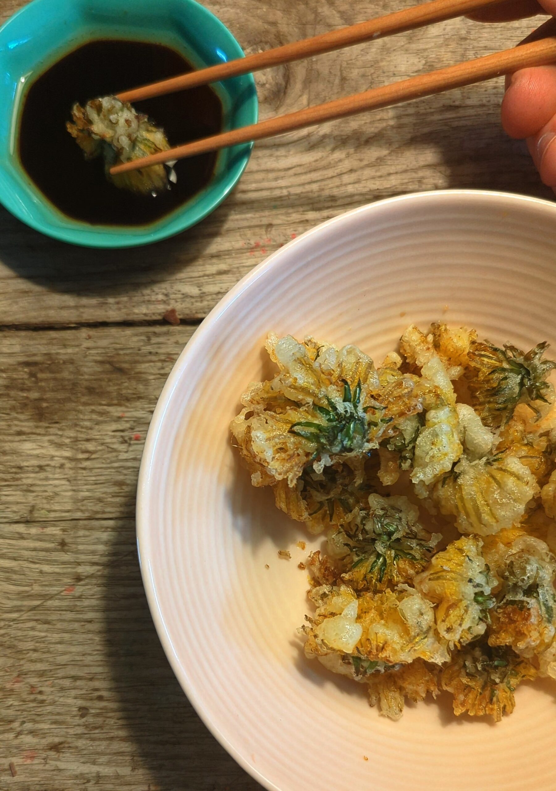 Dandelion tempura in a blush pink bowl with a dipping sauce